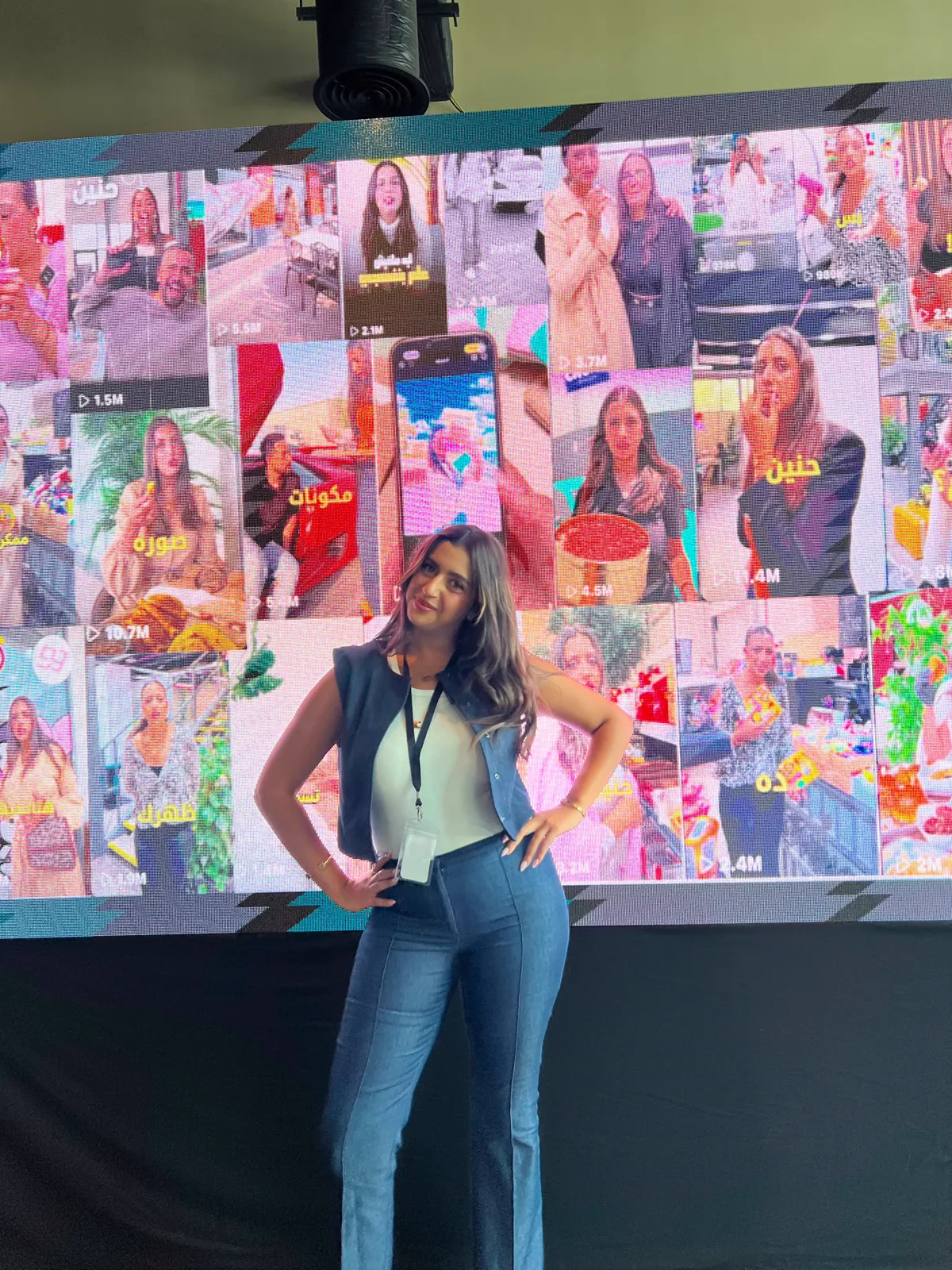 Haneen in front of a screen wall showing her videos, each with millions of views